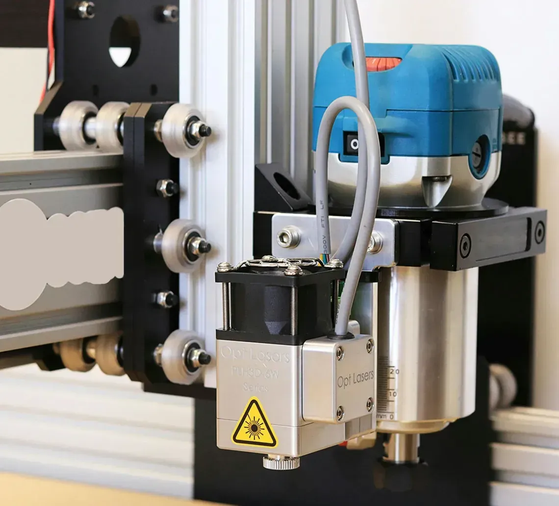 CNC machine with a laser and router attachment, mounted on a metal frame.