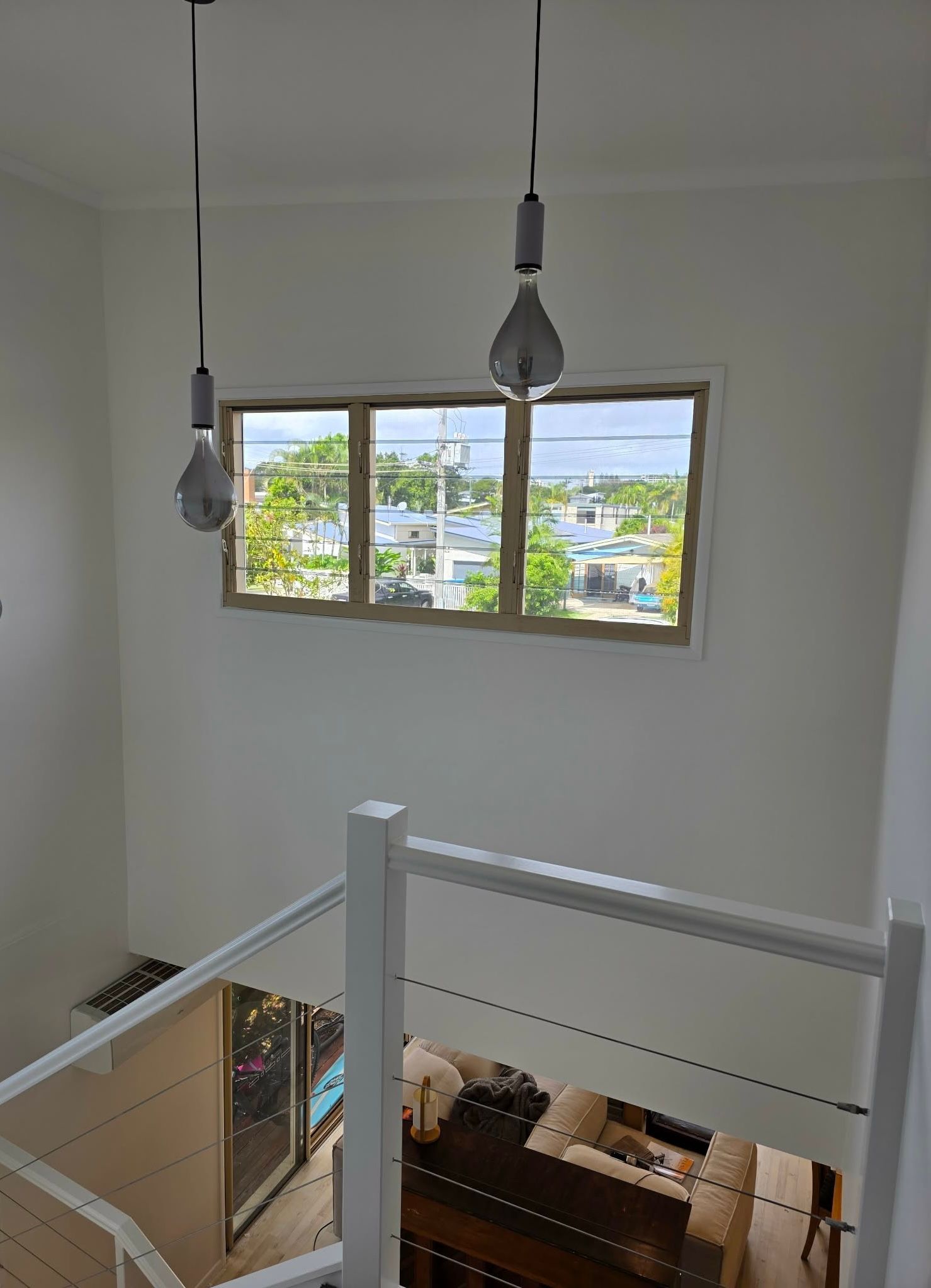 White staircase with window, and two hanging lightbulbs.