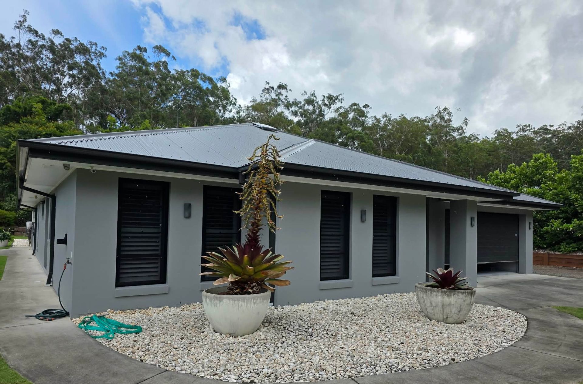Gray house with dark gray garage door, porch, and roof. Driveway leads up to the house — MVP Painting Professionals in Sunshine Coast, QLD
