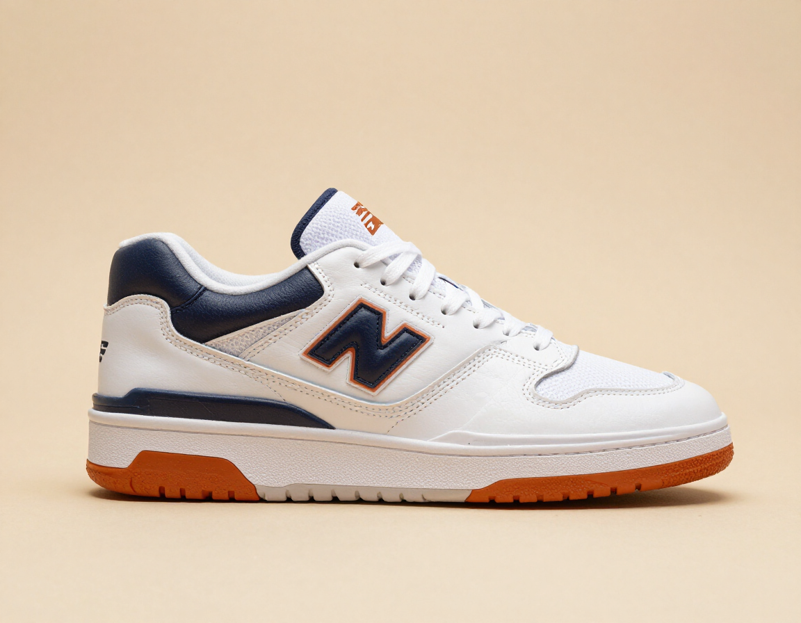 White New Balance sneaker with navy accents and orange sole on a beige background