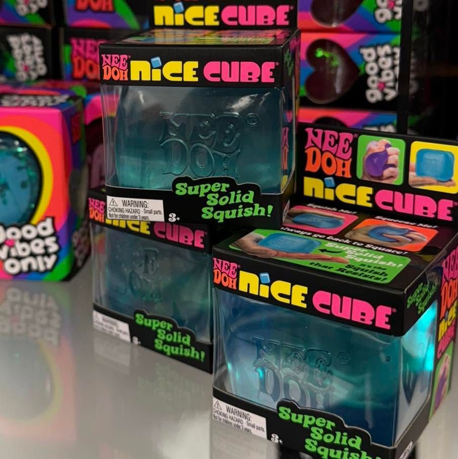 Colorful NEE DOH stacked Nice Cube toy boxes with “Super solid squishy” packaging on a store shelf