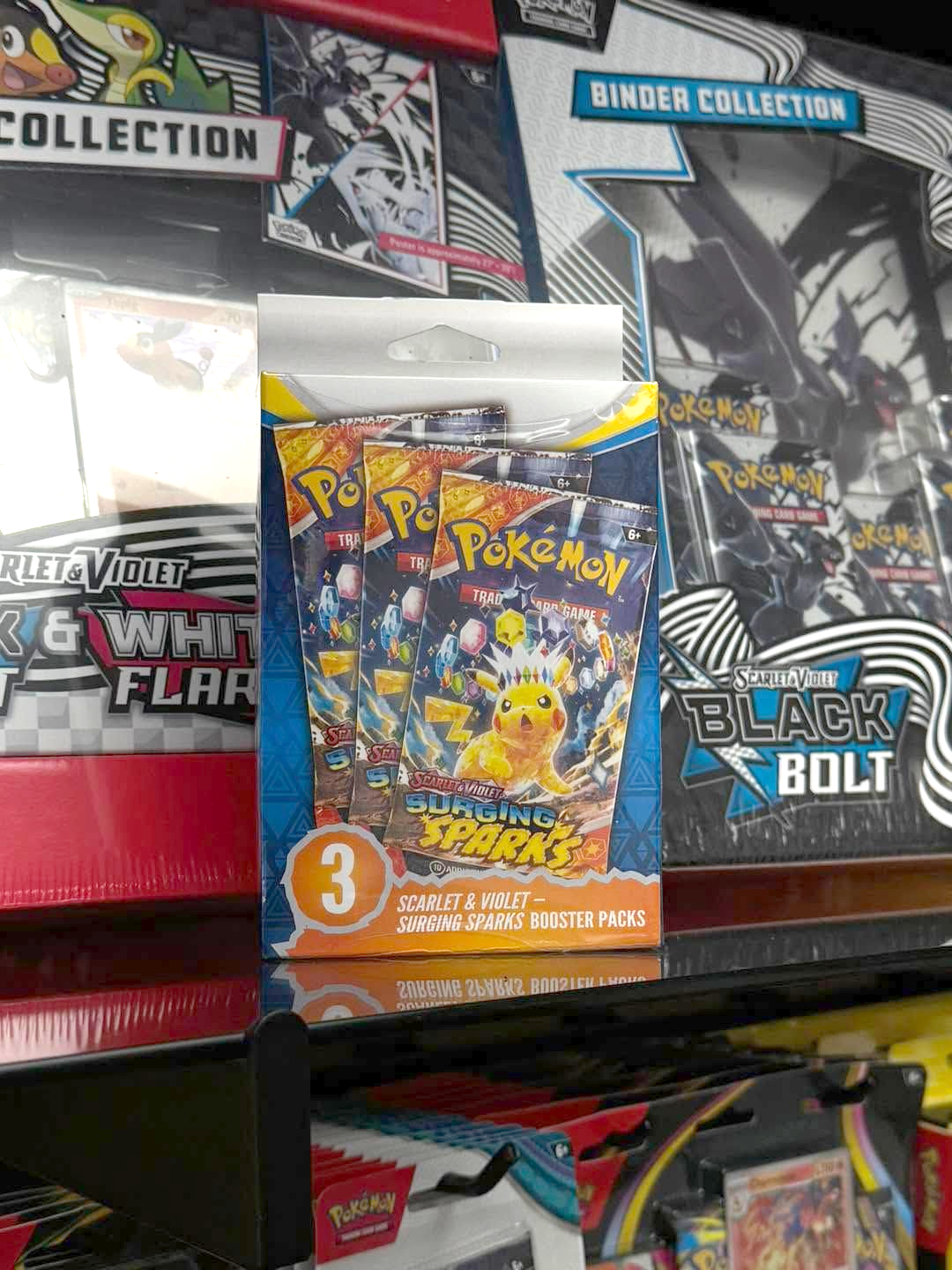 Pokémon trading card packs on a store shelf, featuring Scarlet & Violet: Paldean Fates and Black Bolt packs