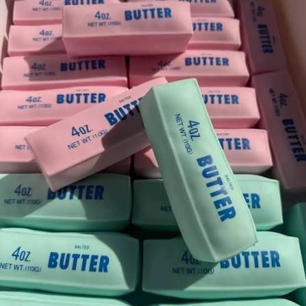 Stacks of wrapped butter sticks in pink and mint green packaging