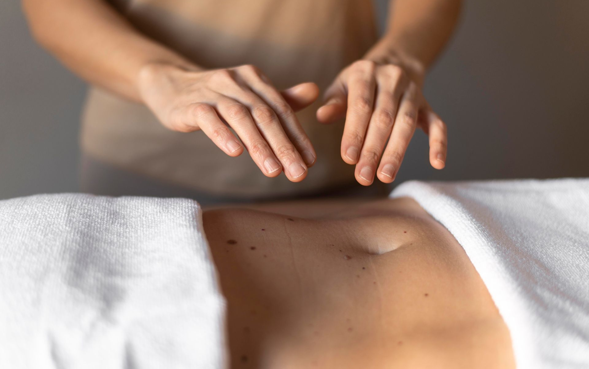 A person receives a back massage while lying on a spa table with closed eyes in a room with candles.
