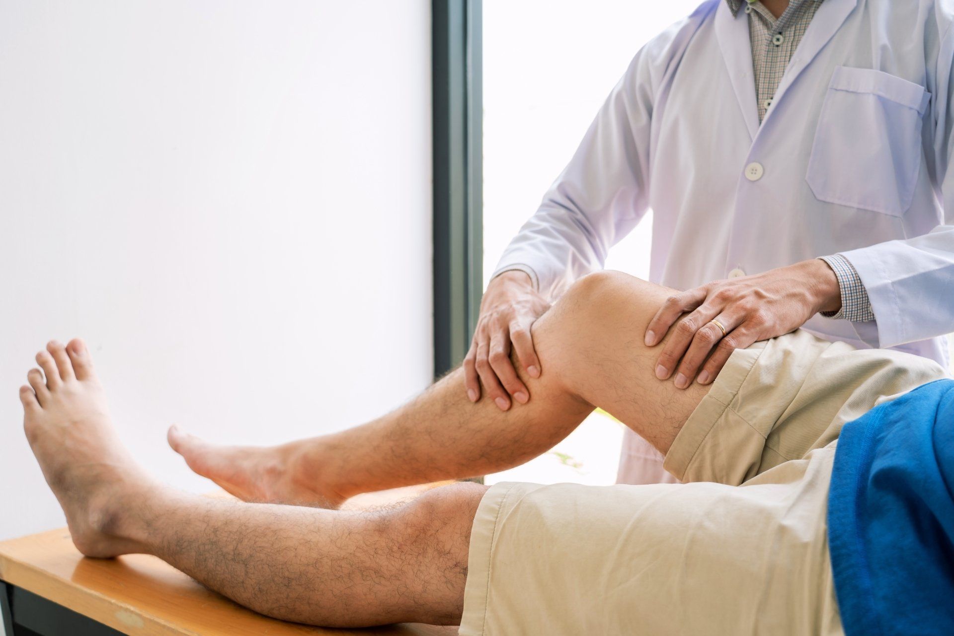 Doctor examining a patient’s knee in a bright clinic room