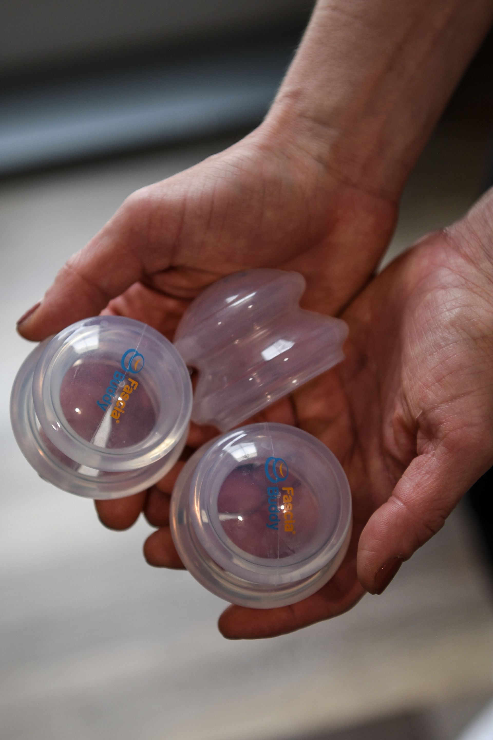 Hands holding three clear cupping therapy devices.
