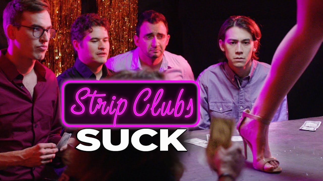 A group of men are sitting around a table watching a stripper.