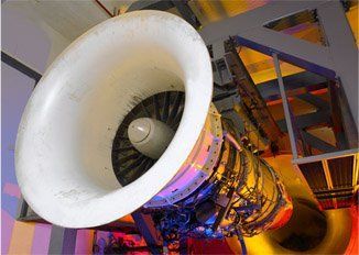 A large rocket engine nozzle inside a test facility, with metal framework and warm lighting.