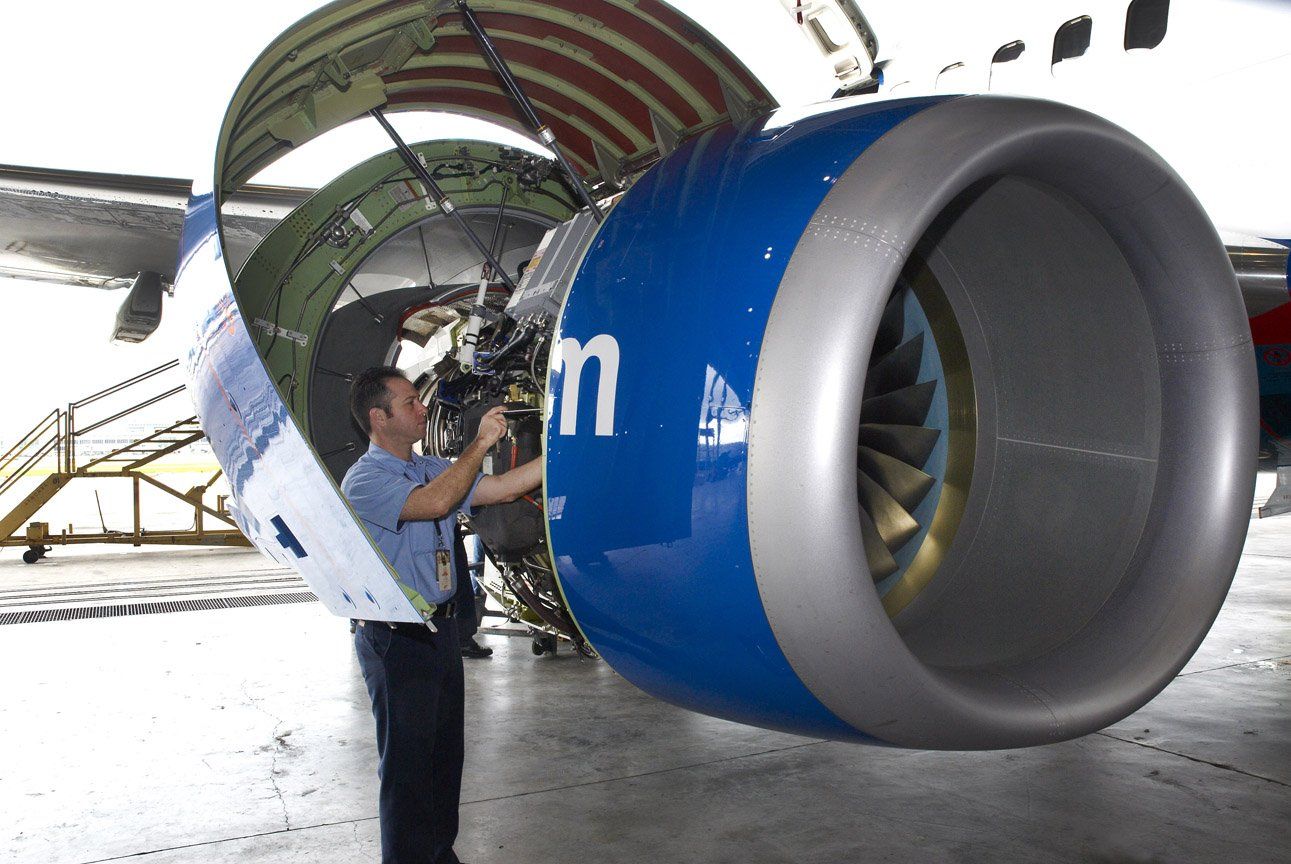 Technician inspects a large jet engine nacelle in a hangar