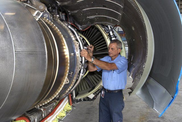 Technician inspecting a large jet engine inside a hangar