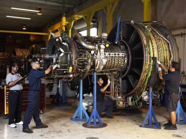 Workers assembling a large jet engine in an industrial workshop