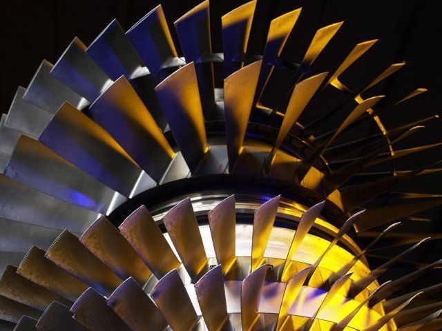 Close-up of a metallic turbine wheel with blue and gold blades against a dark background