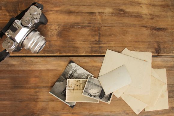 Camera and scattered printed photos on a wooden table
