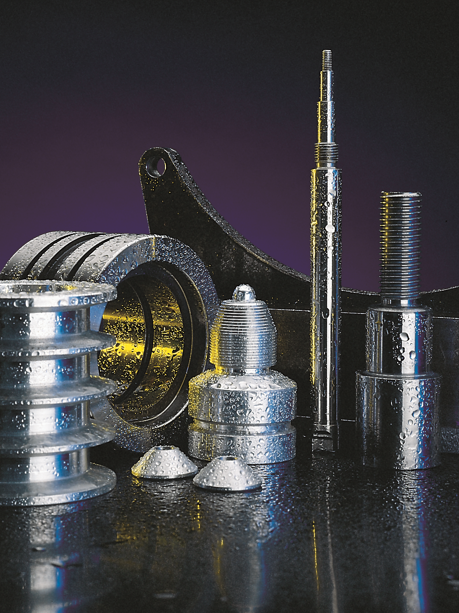 Assorted metal machining parts and threaded fasteners arranged on a dark reflective surface