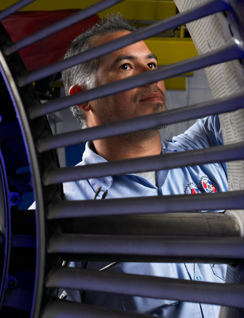 Man in a blue shirt adjusting dark window blinds inside a vehicle or room