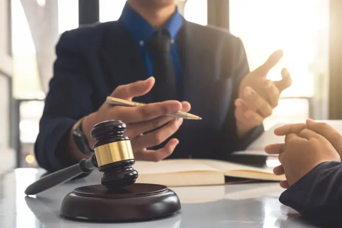 Attorney gesturing during a consultation with a wooden gavel in the foreground.