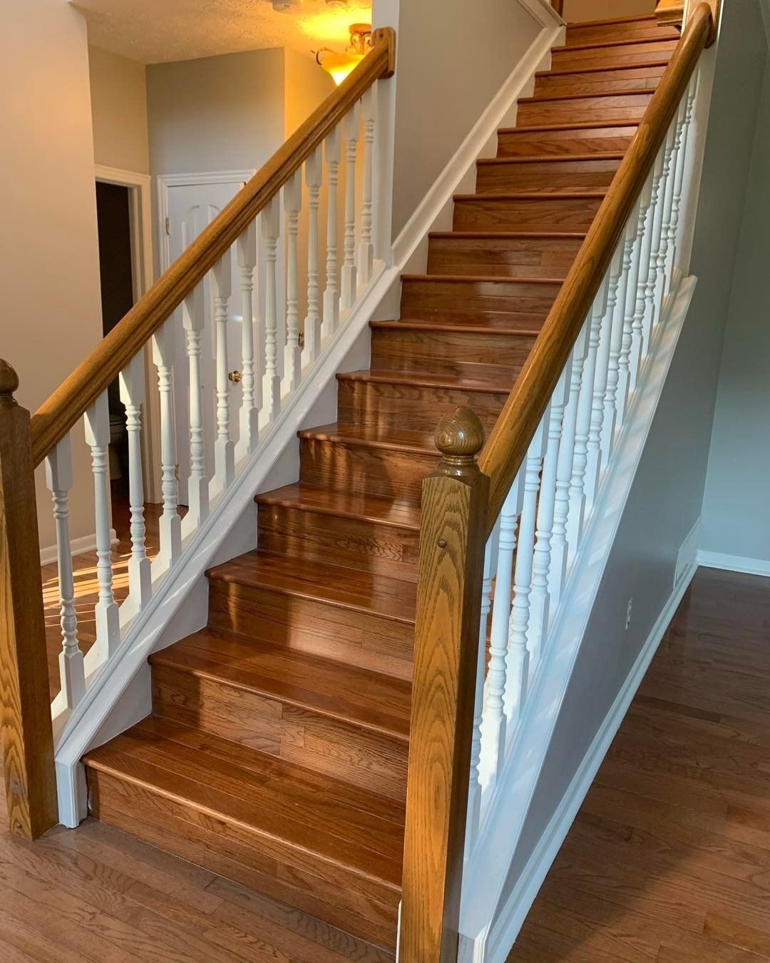 Wooden staircase with oak banisters, white balusters, and hardwood steps in a home.