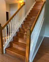 Wooden staircase with oak banisters, white balusters, and hardwood steps in a home.