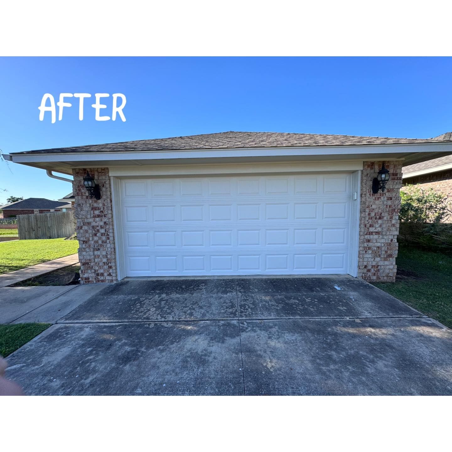 White garage door with stone accents, set against a clear blue sky, concrete driveway. 