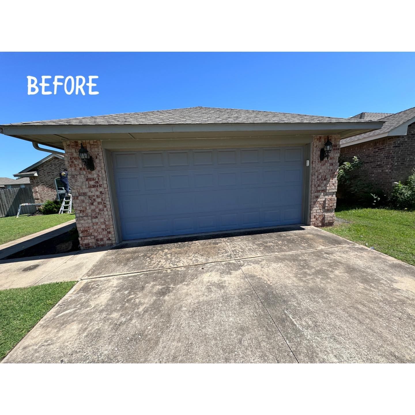 Garage with gray door and brick accents, concrete driveway, and blue sky.