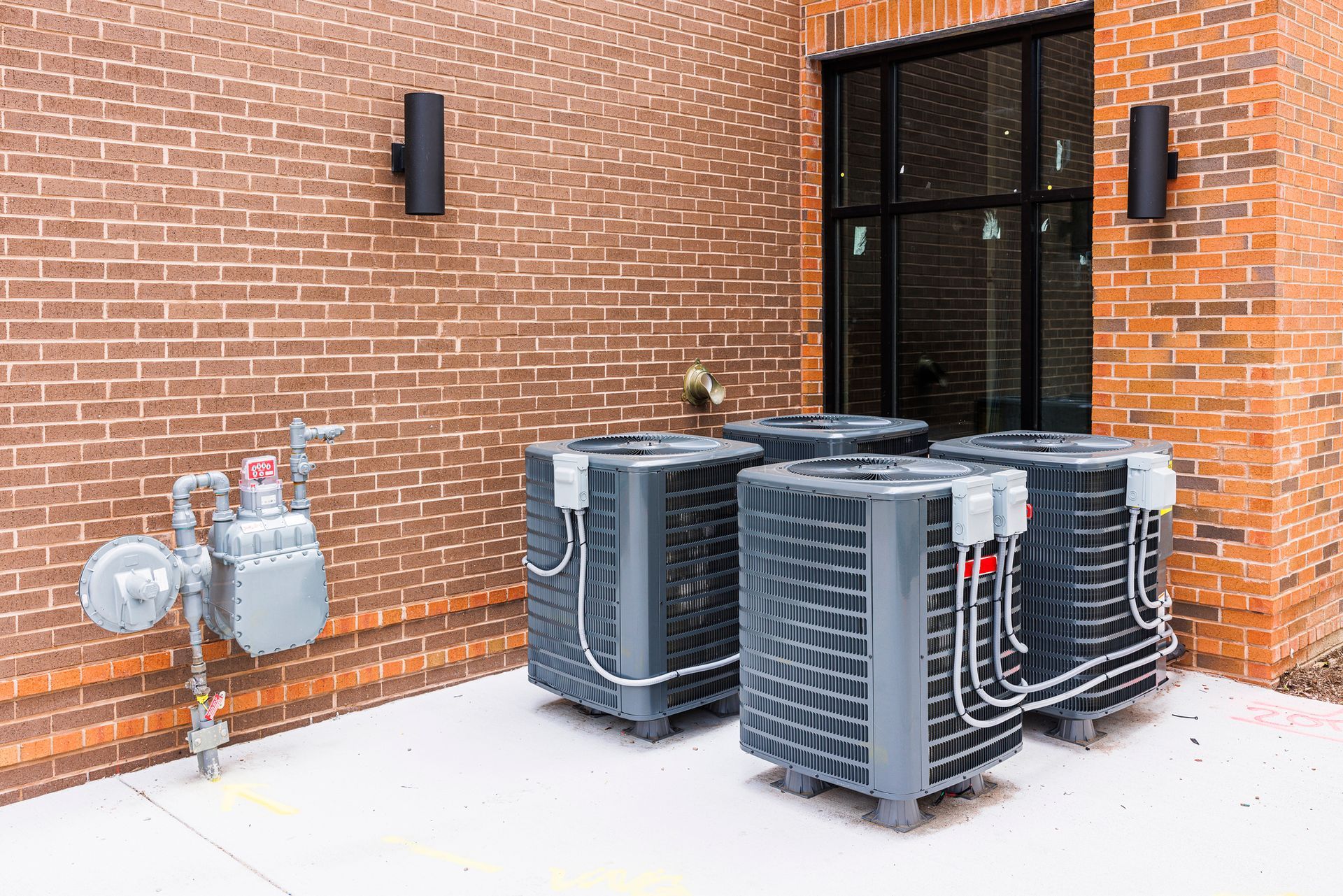 A row of air conditioners are sitting outside of a brick building.