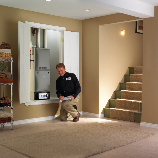 A man is kneeling in front of a wall mounted heater