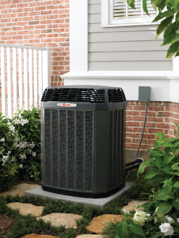 An air conditioner is sitting on the side of a brick house.