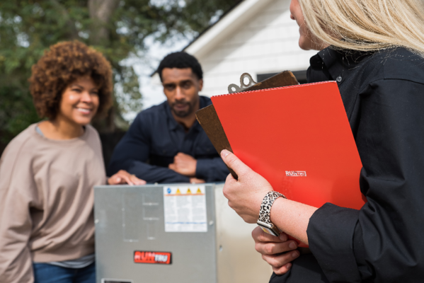 A woman is holding a clipboard and talking to a man and woman