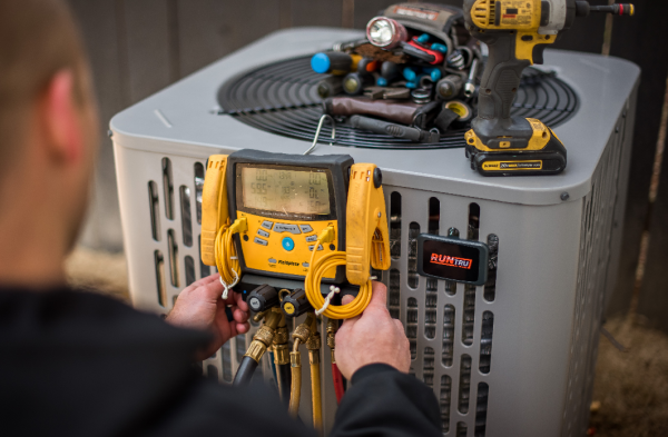 Comfort Control technician is working on an air conditioner with a drill.