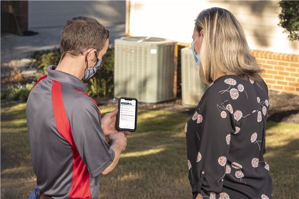 Comfort Control technician and a woman are looking at a cell phone.