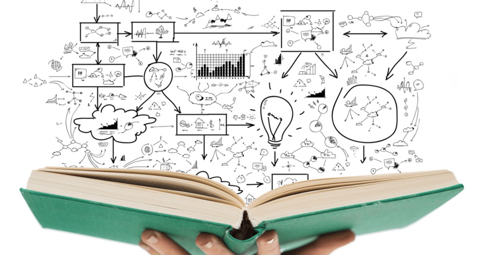 A person is holding an open book with drawings coming out of it