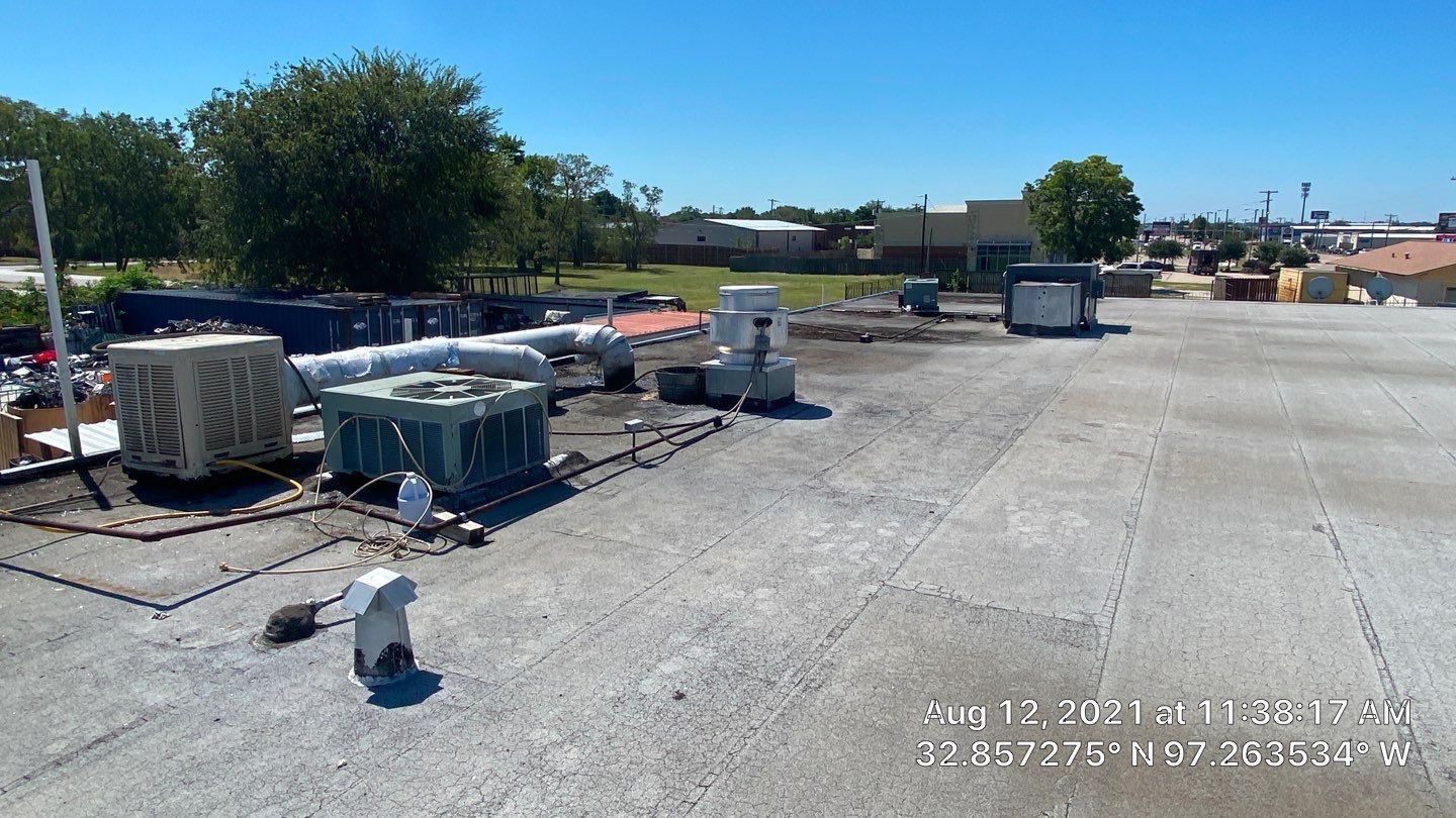 Rooftop with HVAC units, surrounding buildings, and a clear blue sky on a sunny day.