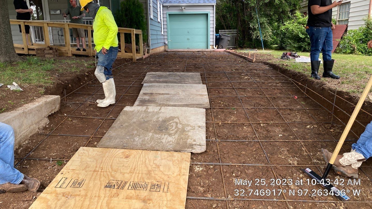 Workers preparing a driveway for concrete. Steel rebar grid laid on the ground.