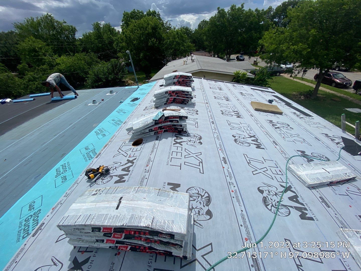 Roofers working on a house roof, bundles of shingles are placed on the roof.