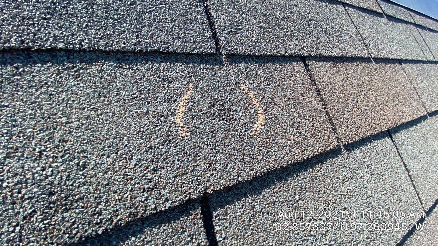 Close-up of weathered asphalt roof shingles with discolored areas in the middle.