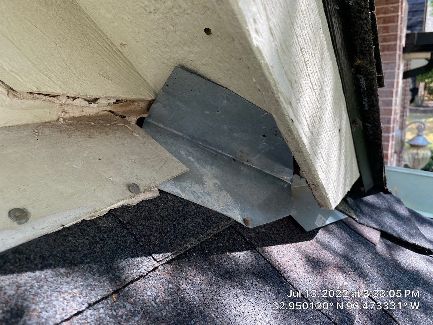 Close-up of a roof corner showing metal flashing where the roof meets the siding.