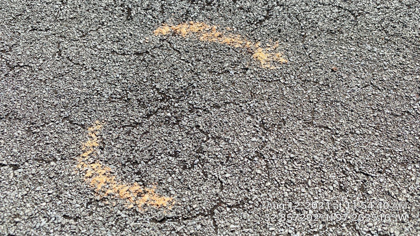Close-up of weathered gray asphalt with a faded yellow semi-circle marking.