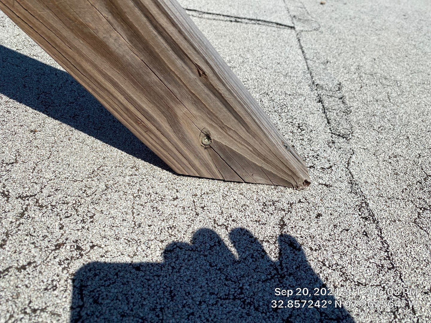 Wooden beam on a textured gray surface, casting a shadow.
