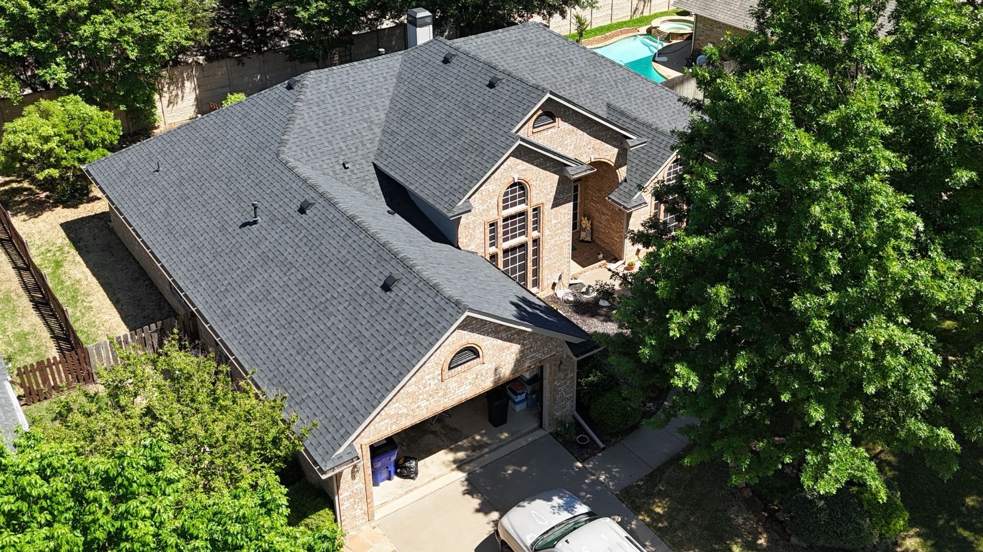 Aerial view of a large house with a dark gray roof, a brick exterior, and a two-car garage.
