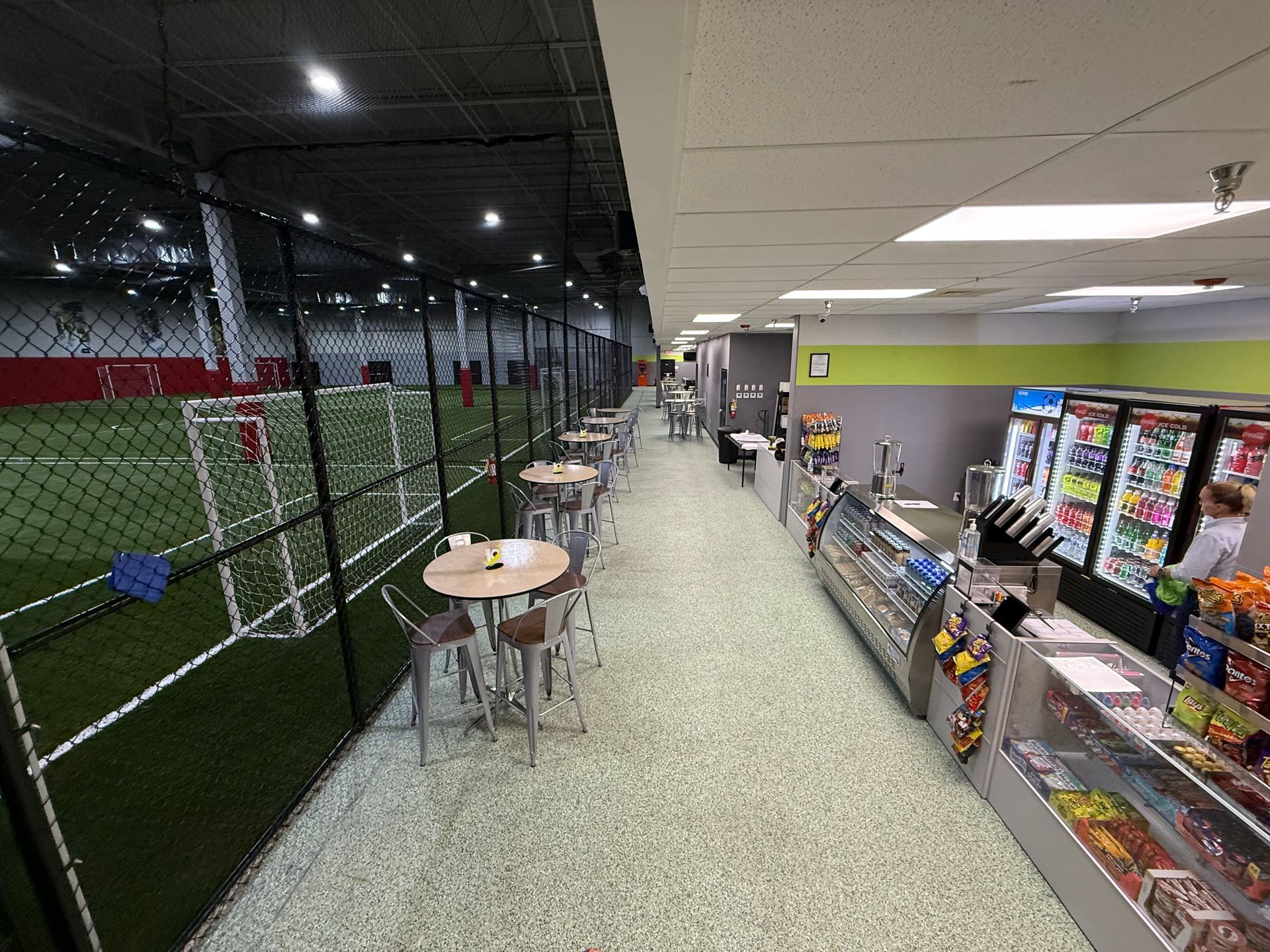 Indoor soccer field with cafe seating along the side. Snack counter in foreground.