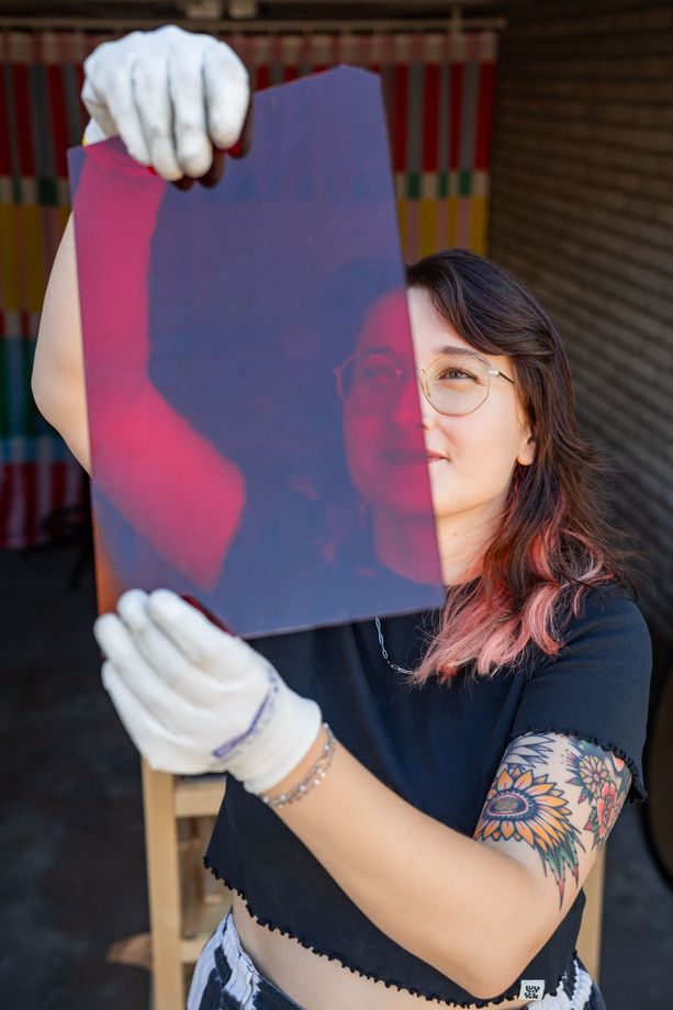 Lieke Kleverwal houdt een vel roze glas omhoog tegen het licht