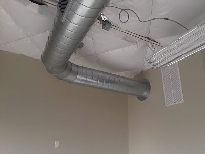 Metal HVAC ductwork against a beige wall and white ceiling.