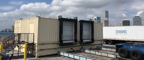 Unidades de climatización industrial en la azotea y conductos sobre un edificio, con un camión al lado y cielo nublado