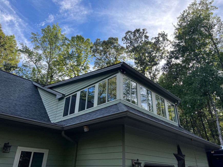 The roof of a house with a lot of windows and trees in the background.