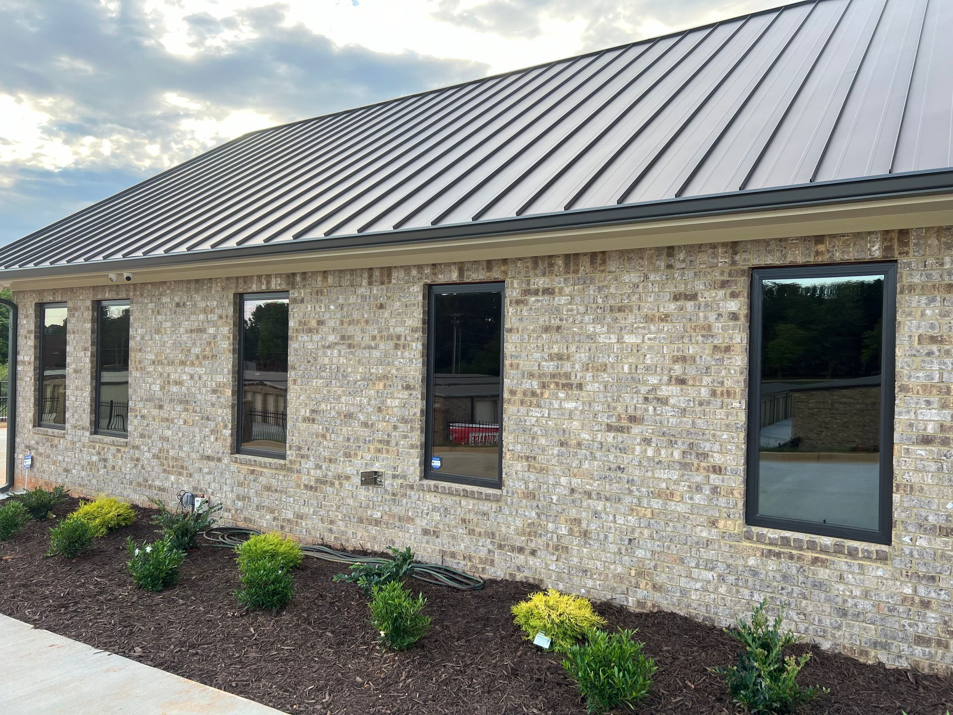 A brick building with a metal roof and a lot of windows.