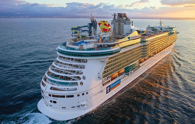 Cruise ship sailing on the ocean at sunset, with water slides, and yellow and blue accents.