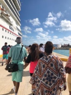 People walking toward a cruise ship on a sunny pier.