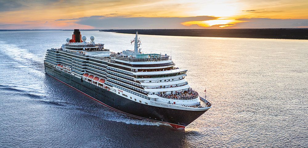 Cruise ship sailing on a body of water, with sunset in the background.