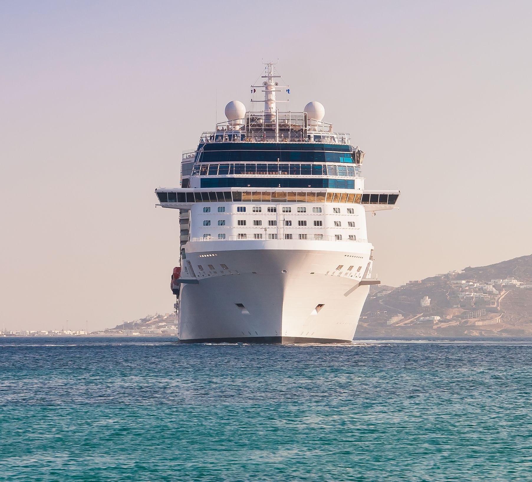 Cruise ship sailing on a turquoise ocean, with a clear blue sky in the background.
