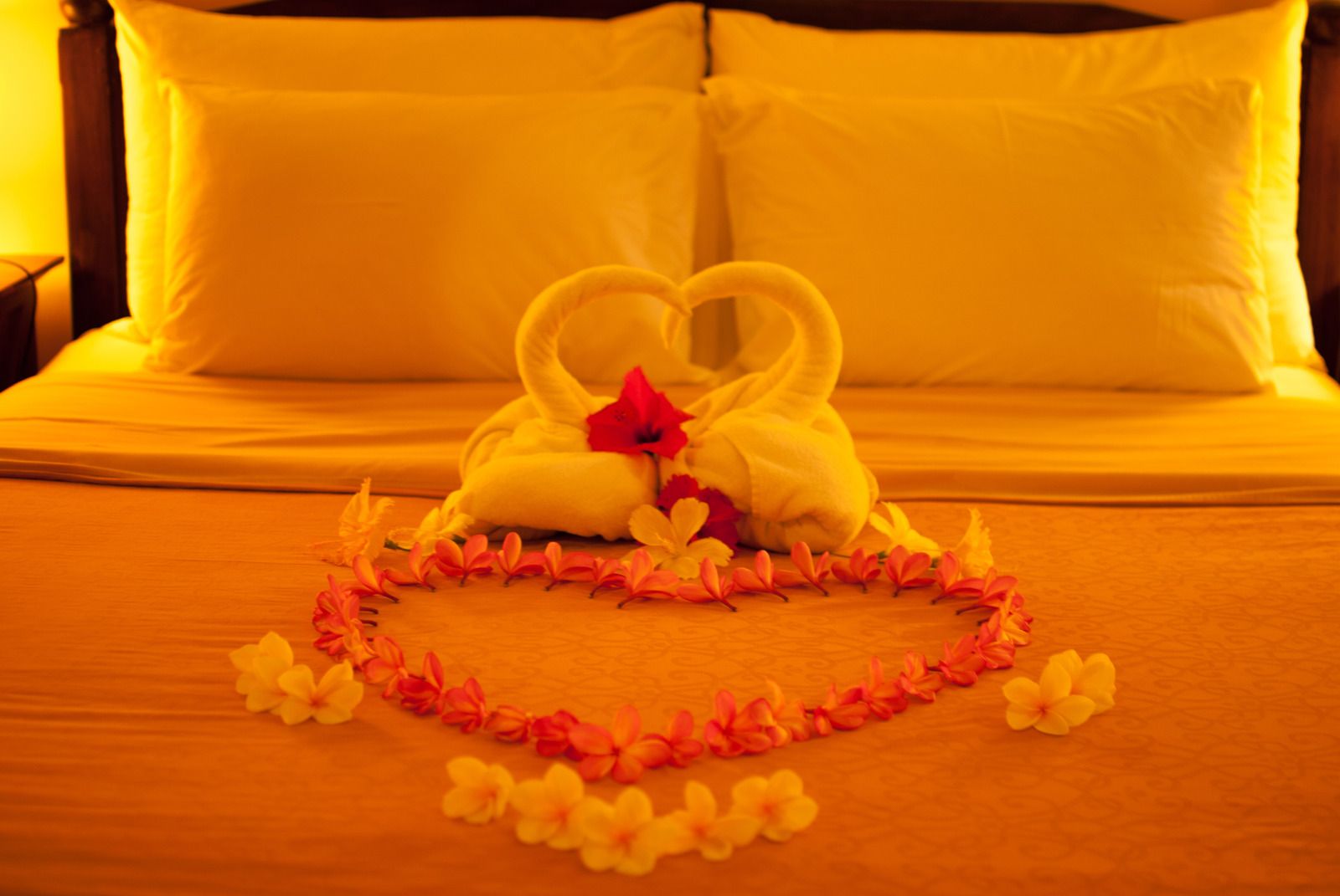 Two towel swans and flower heart on a bed, for a romantic setting.